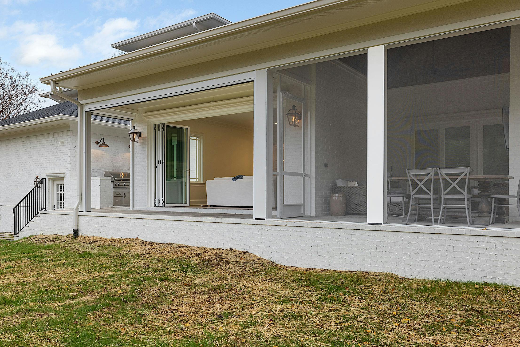 A white house with a patio featuring glass walls