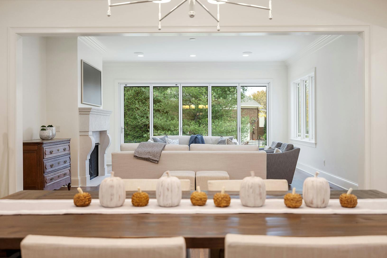 A dining room with a white table and chairs featuring slimmed Aluminum Framed Folding Glass Walls
