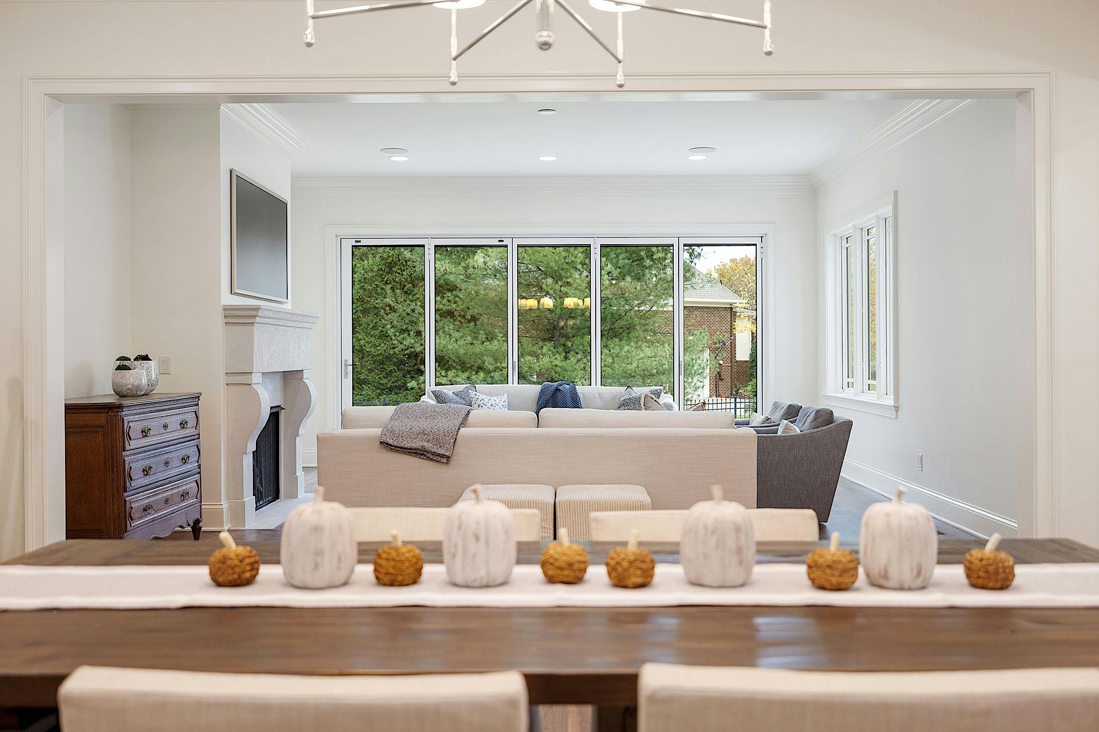 A dining room with a white table and chairs featuring slimmed Aluminum Framed Folding Glass Walls