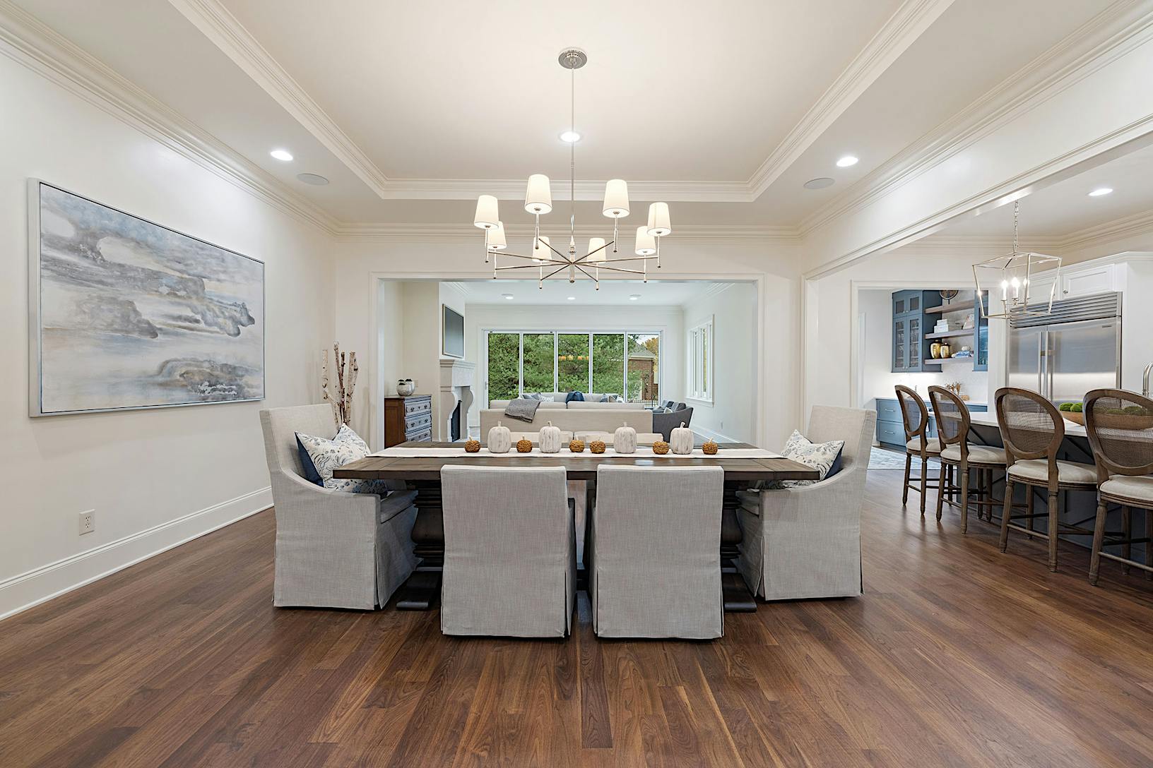 A dining room with folding glass walls hardwood floors and a chandelier