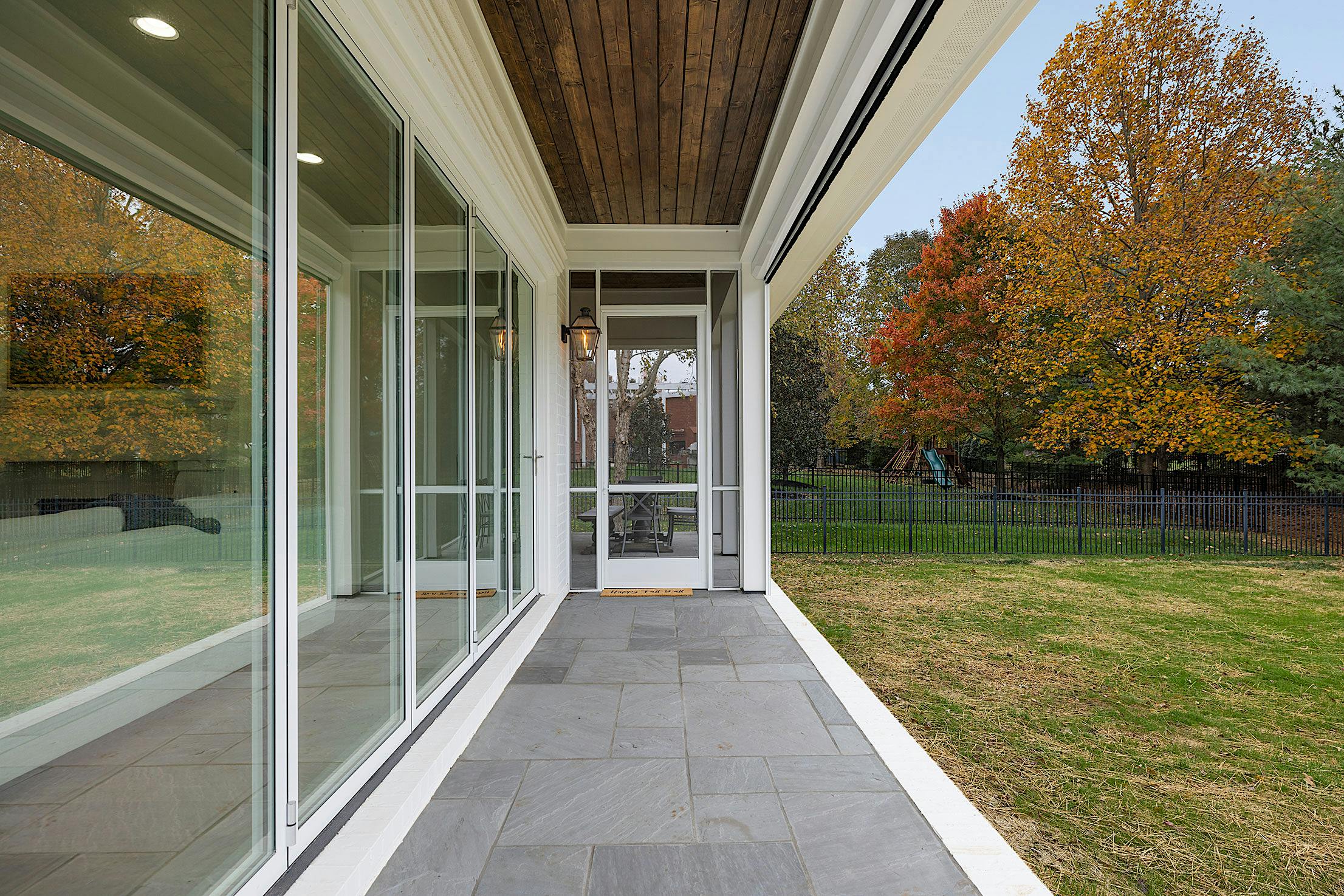 A porch with folding glass walls and a grassy area
