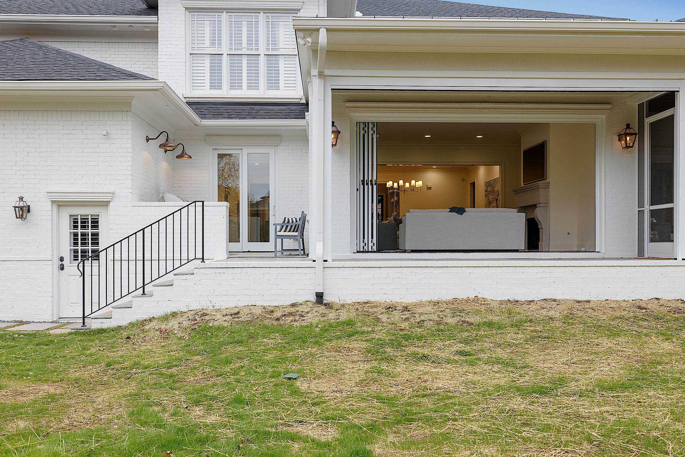 A white house with a patio featuring folding patio doors