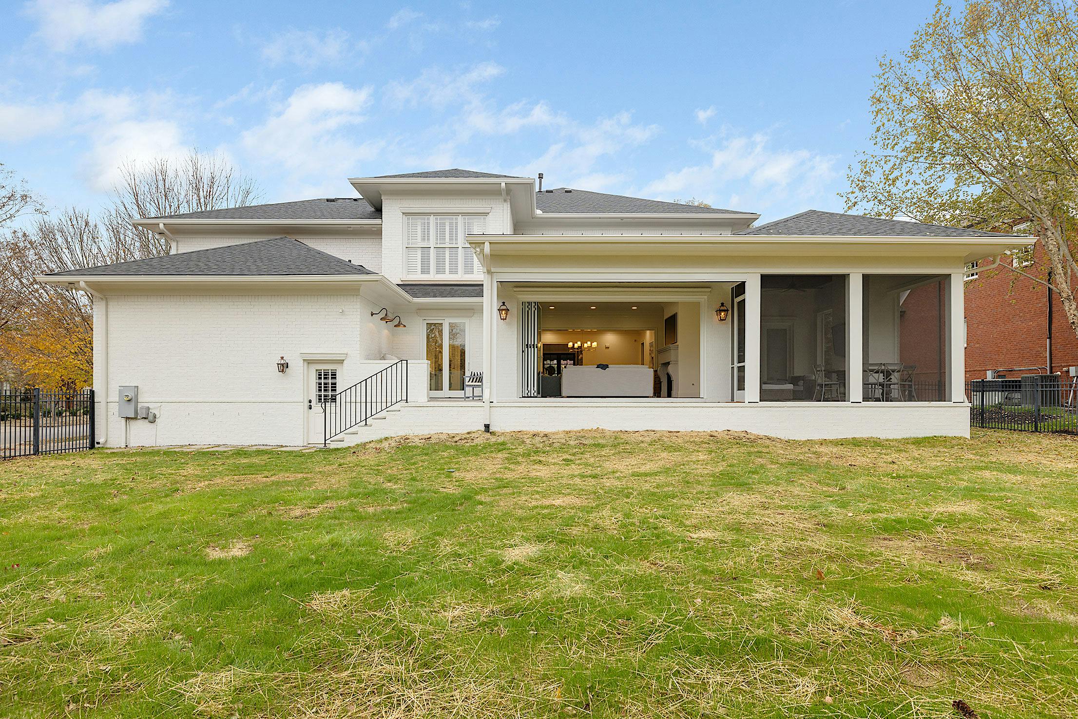 A white house with a patio featuring exterior glass wall panels