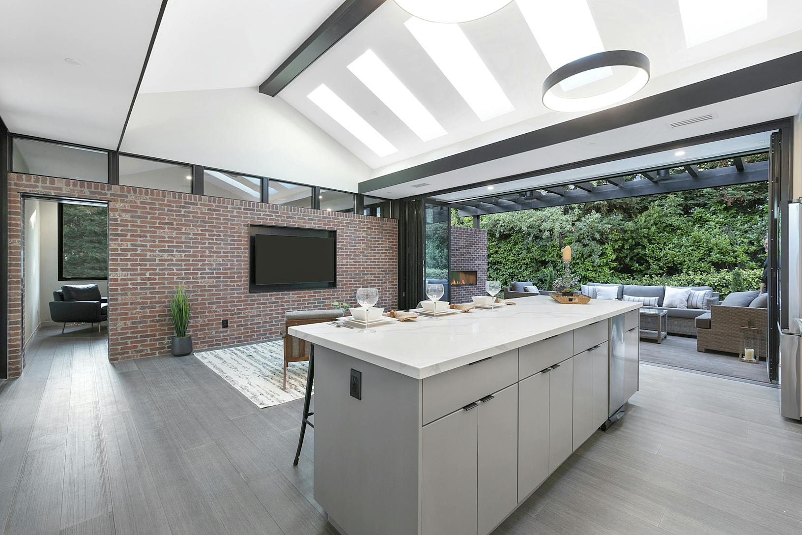 A modern kitchen with a large island featuring folding patio doors