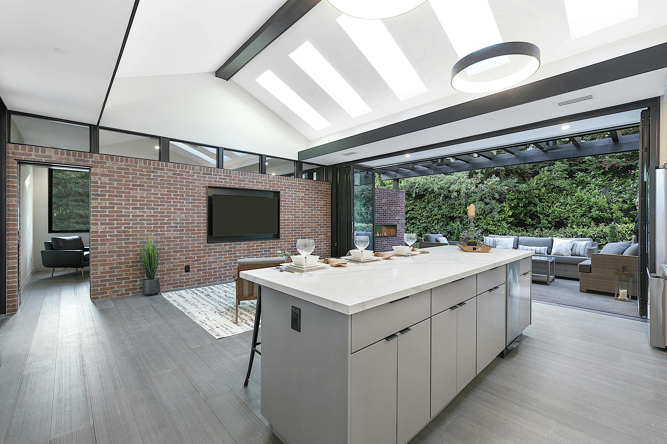 A modern kitchen with a large island featuring folding patio doors