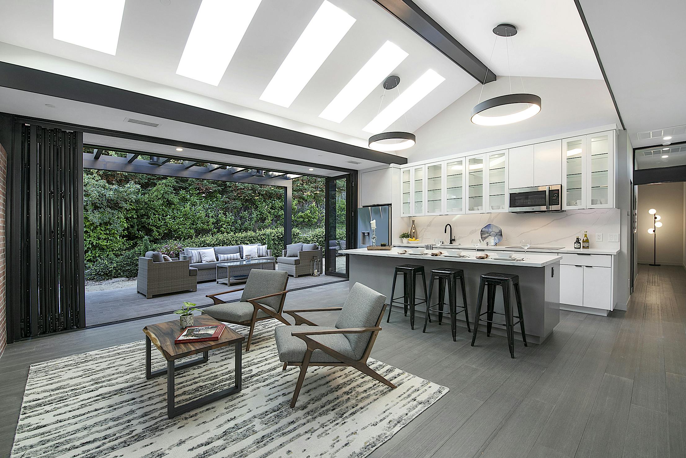 A modern ADU with kitchen and dining room with folding glass walls and a skylight