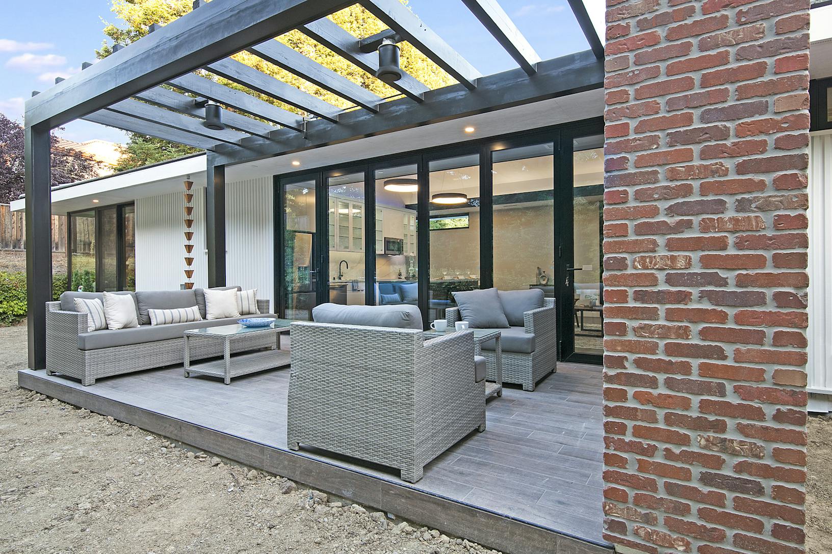 A modern patio with furniture and a brick wall featuring an Aluminum Clad Folding Glass Wall