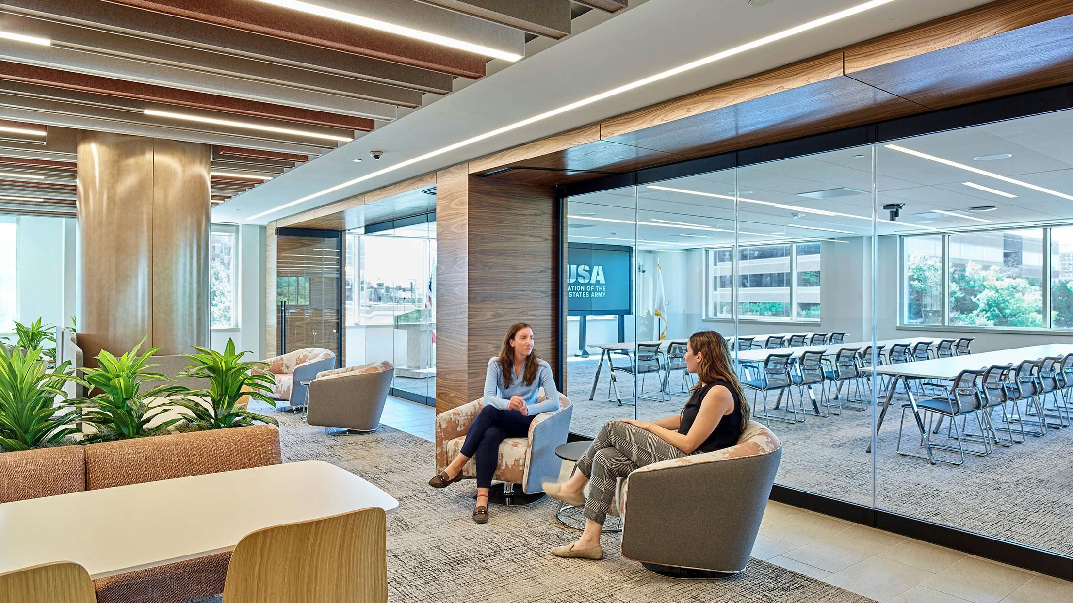 A group of people sitting in a conference room with frameless glass partitions