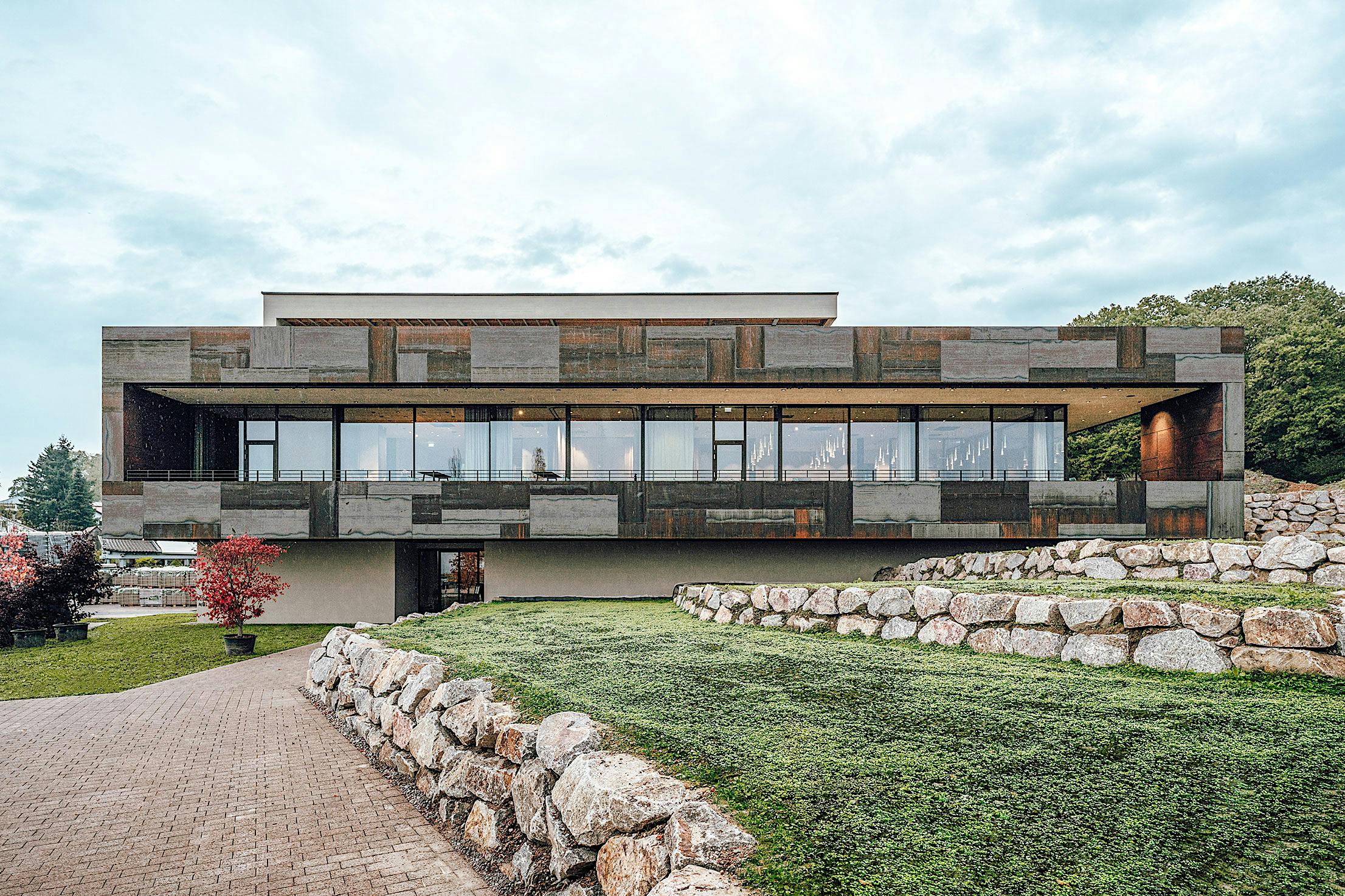 Winery on a hillside with commercial glass walls next to a stone wall