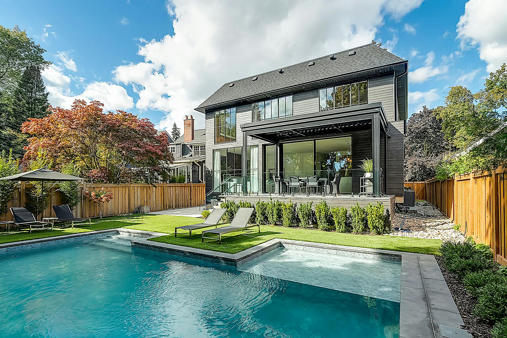 A modern home with sliding glass walls and a swimming pool in the backyard