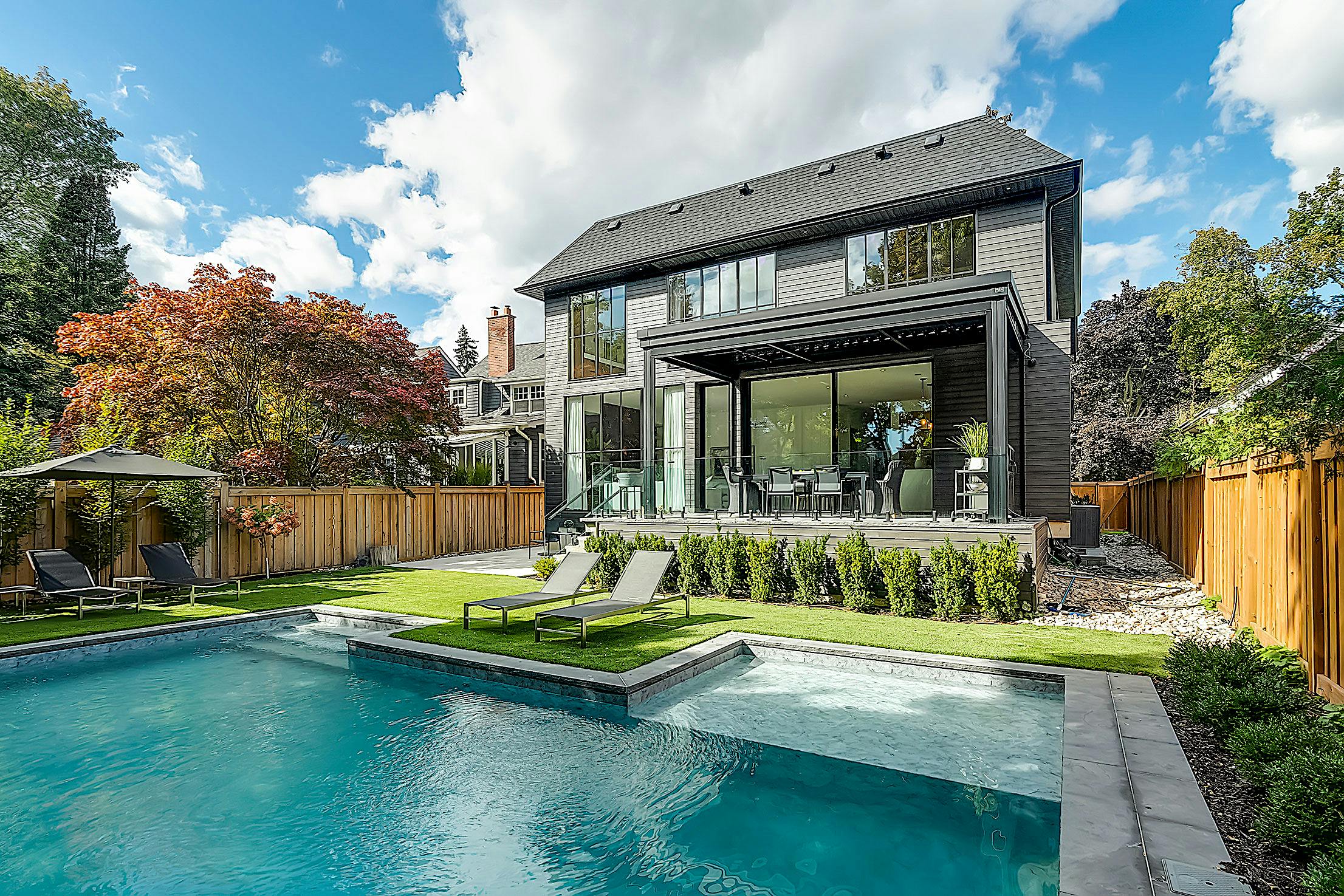 A modern home with sliding glass walls and a swimming pool in the backyard