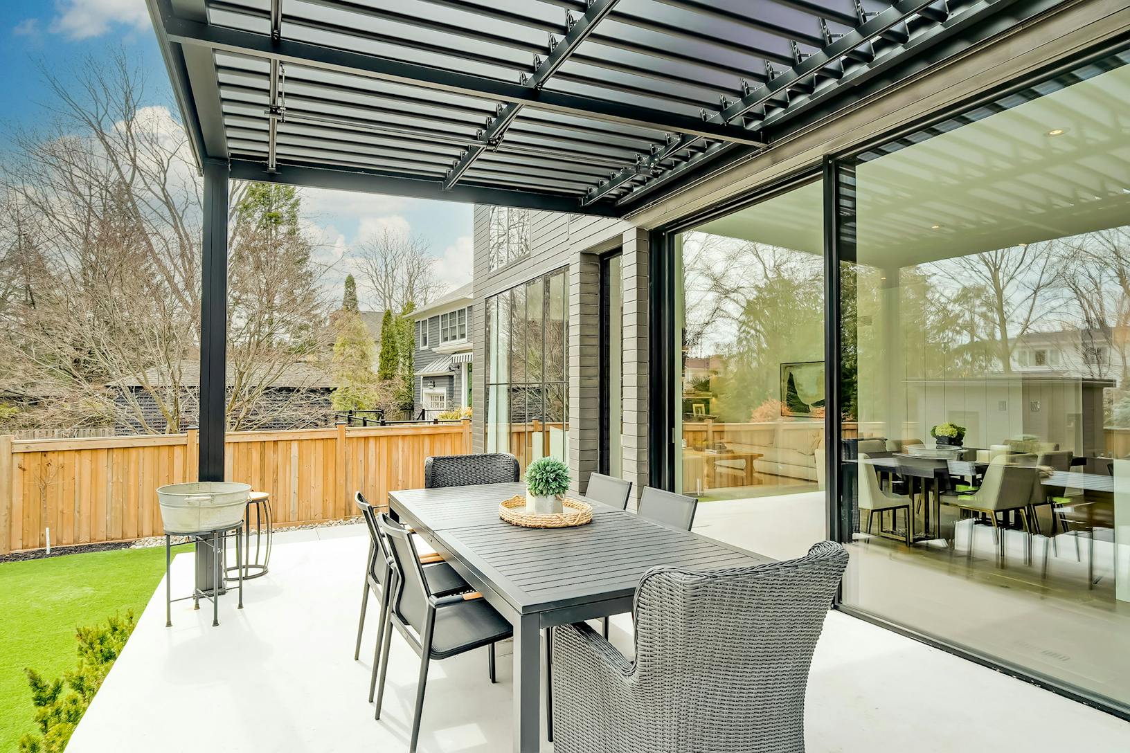 A modern patio with large glass walls and a dining table and chairs