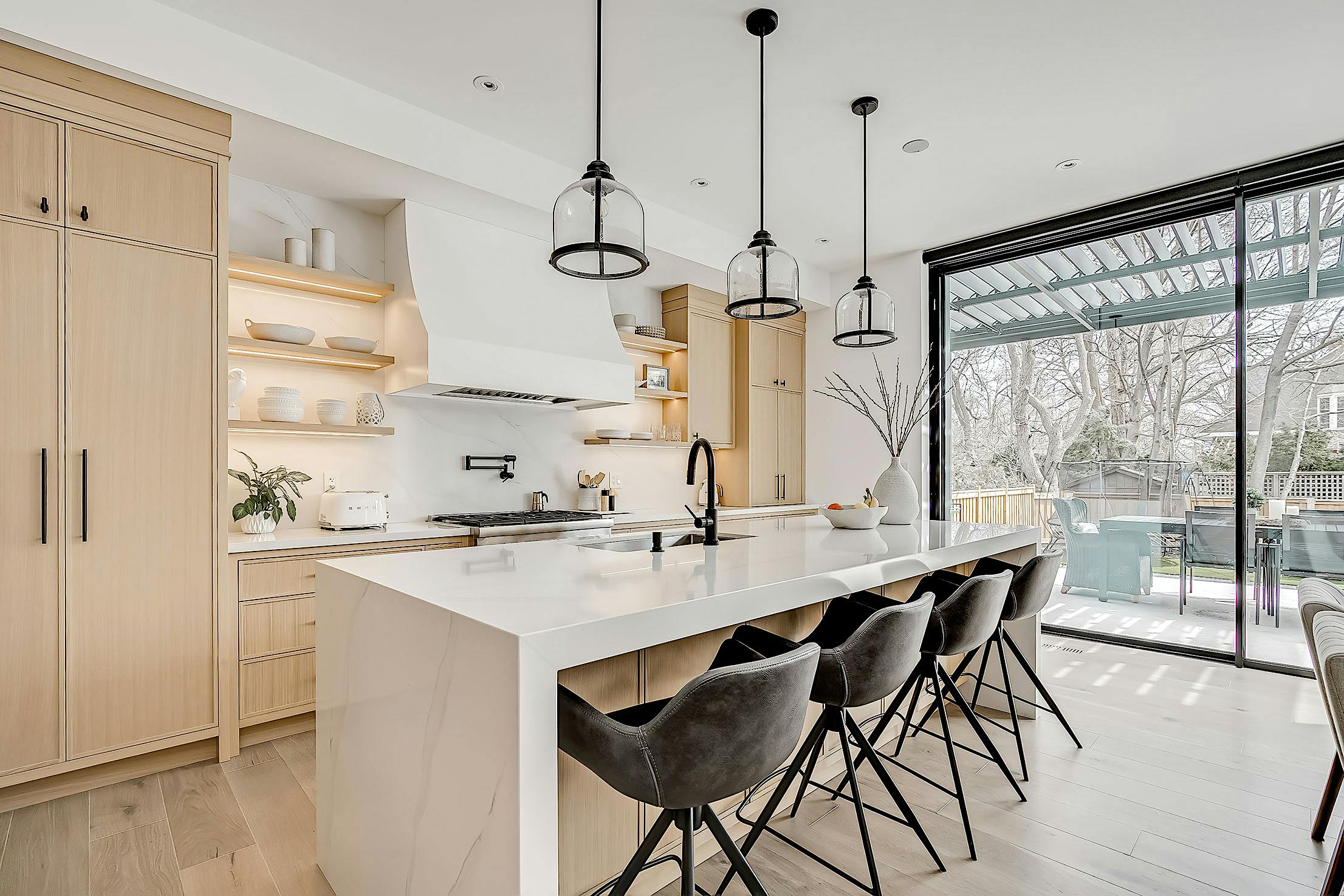 A modern kitchen with a large island and minimal sliding glass walls