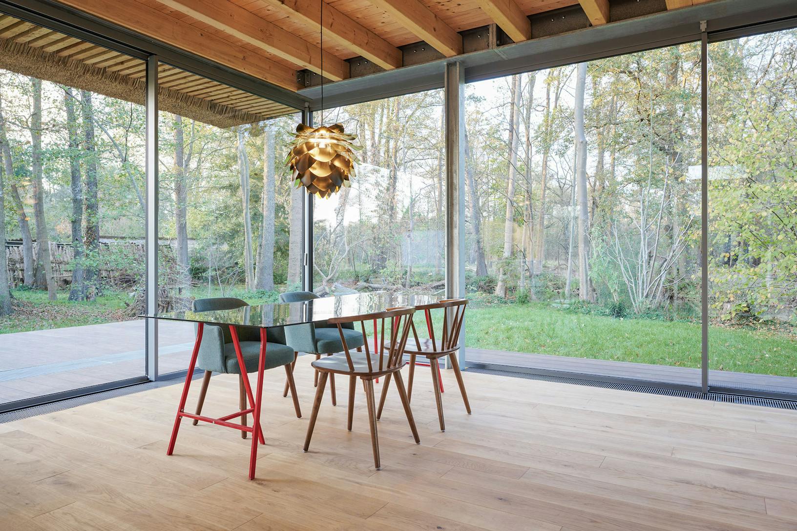 A dining room with minimal sliding glass walls, allowing abundant natural light to flood the space