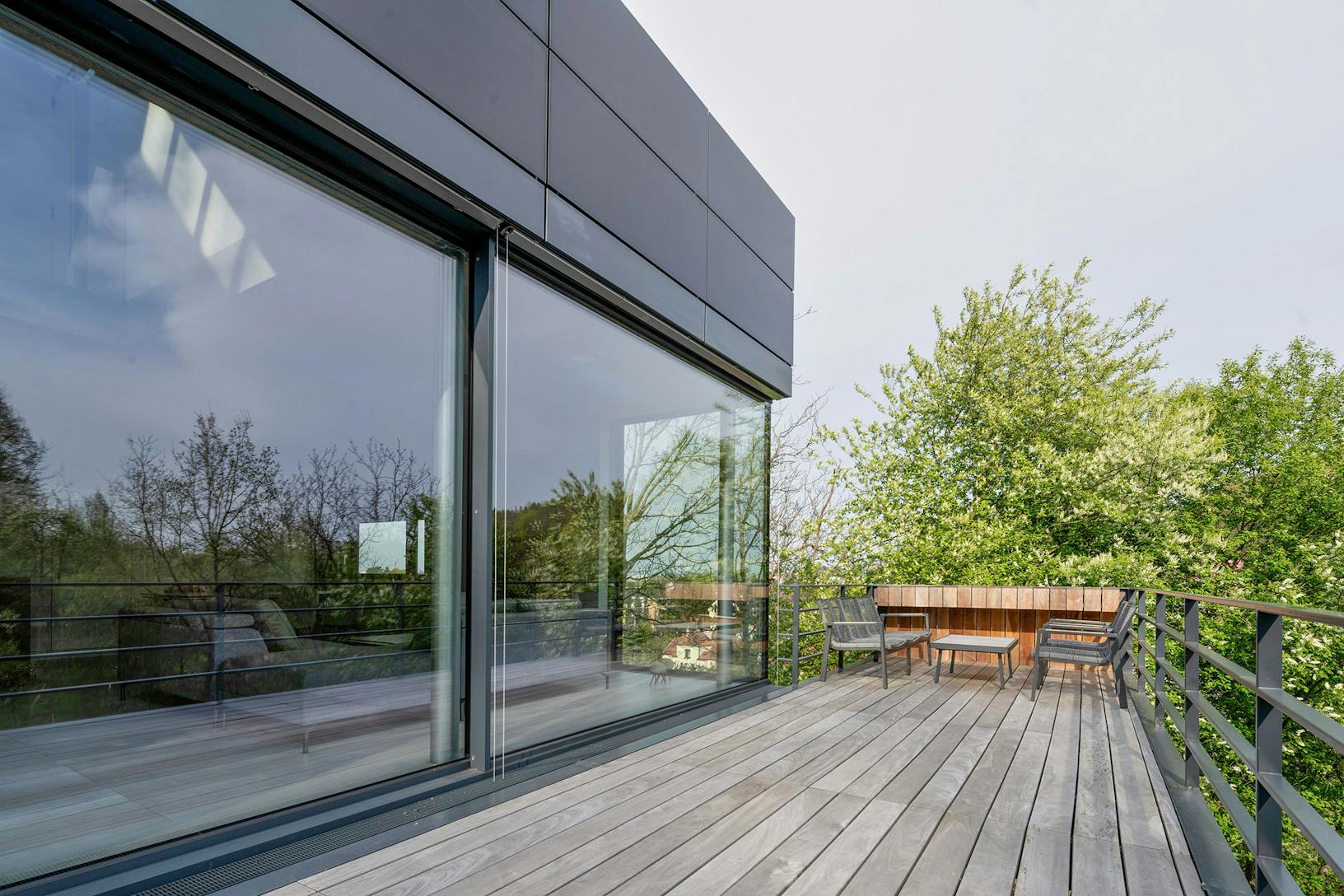 A modern house with a wooden deck and large sliding glass doors