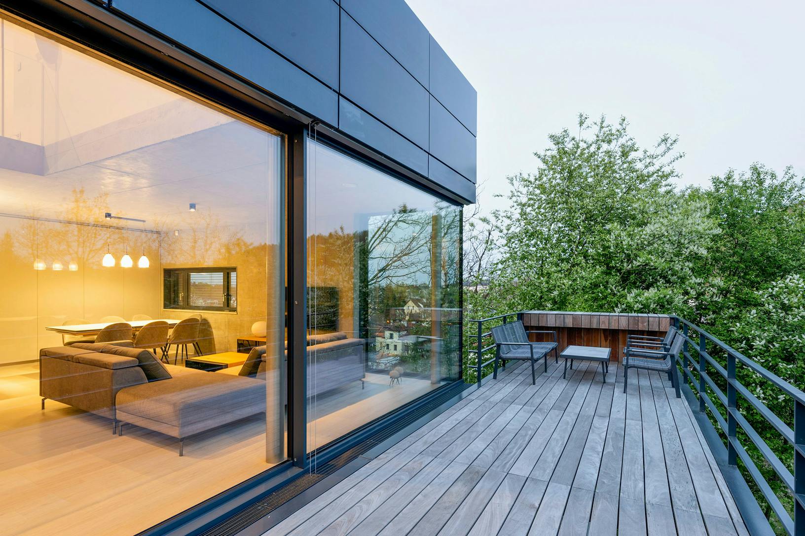 A modern house with a wooden deck and large opening glass walls