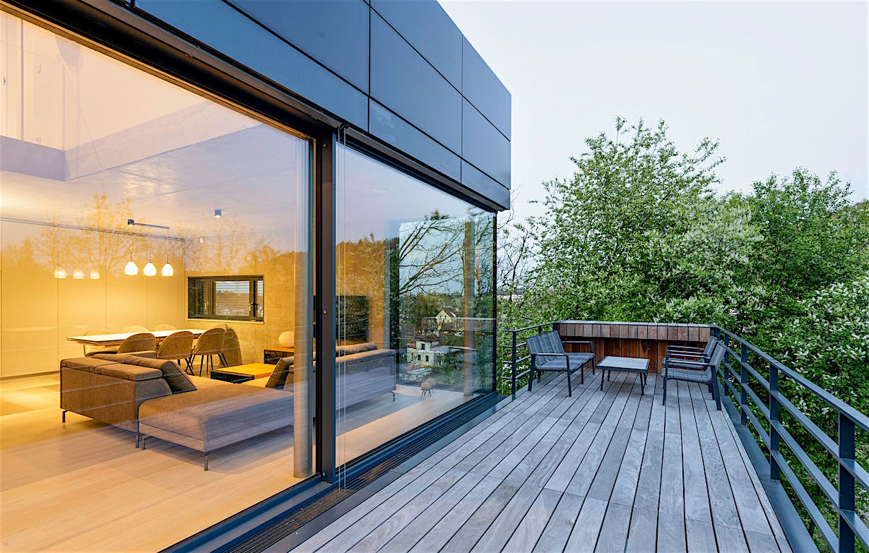 A modern house with a wooden deck and large opening glass walls