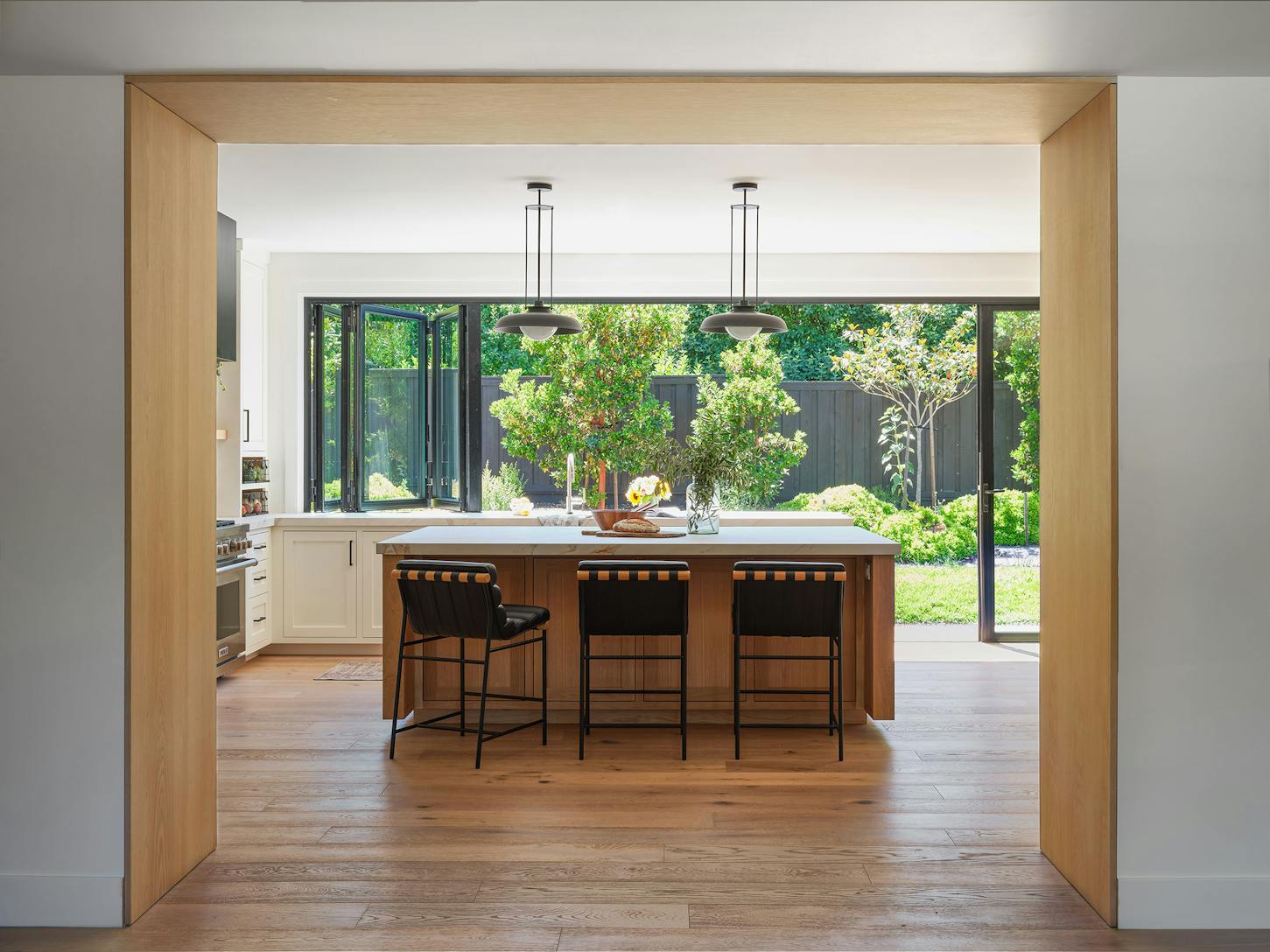 A modern kitchen with wood floors and a view of the outdoors through a window and door combination