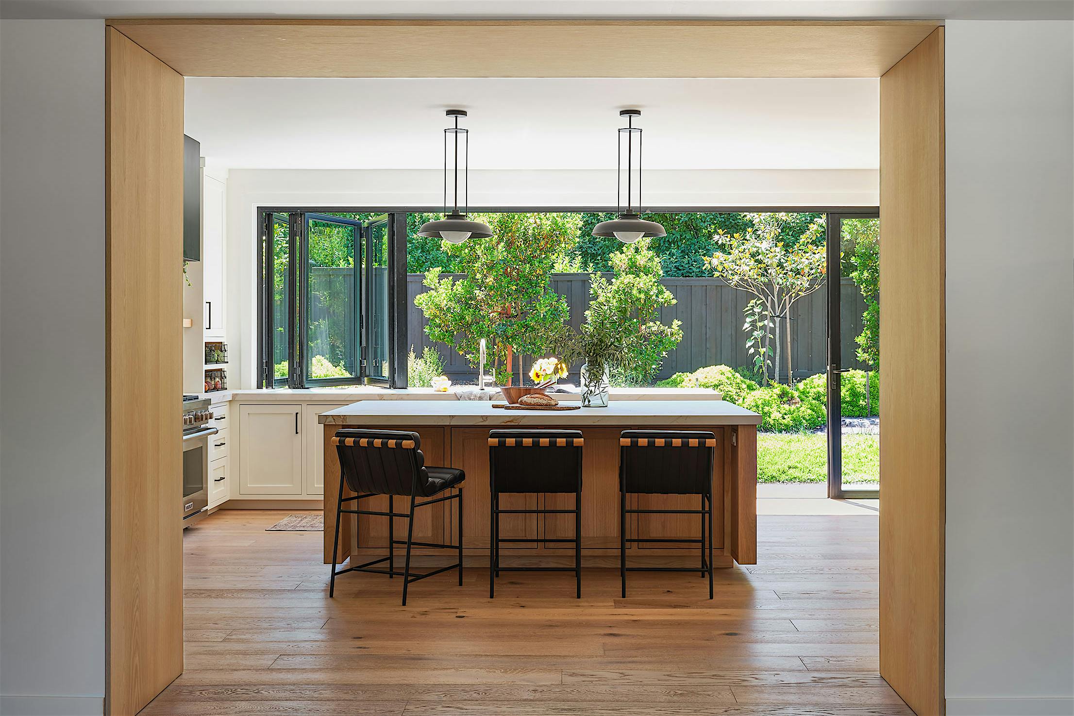 A modern kitchen with wood floors and a view of the outdoors through a window and door combination
