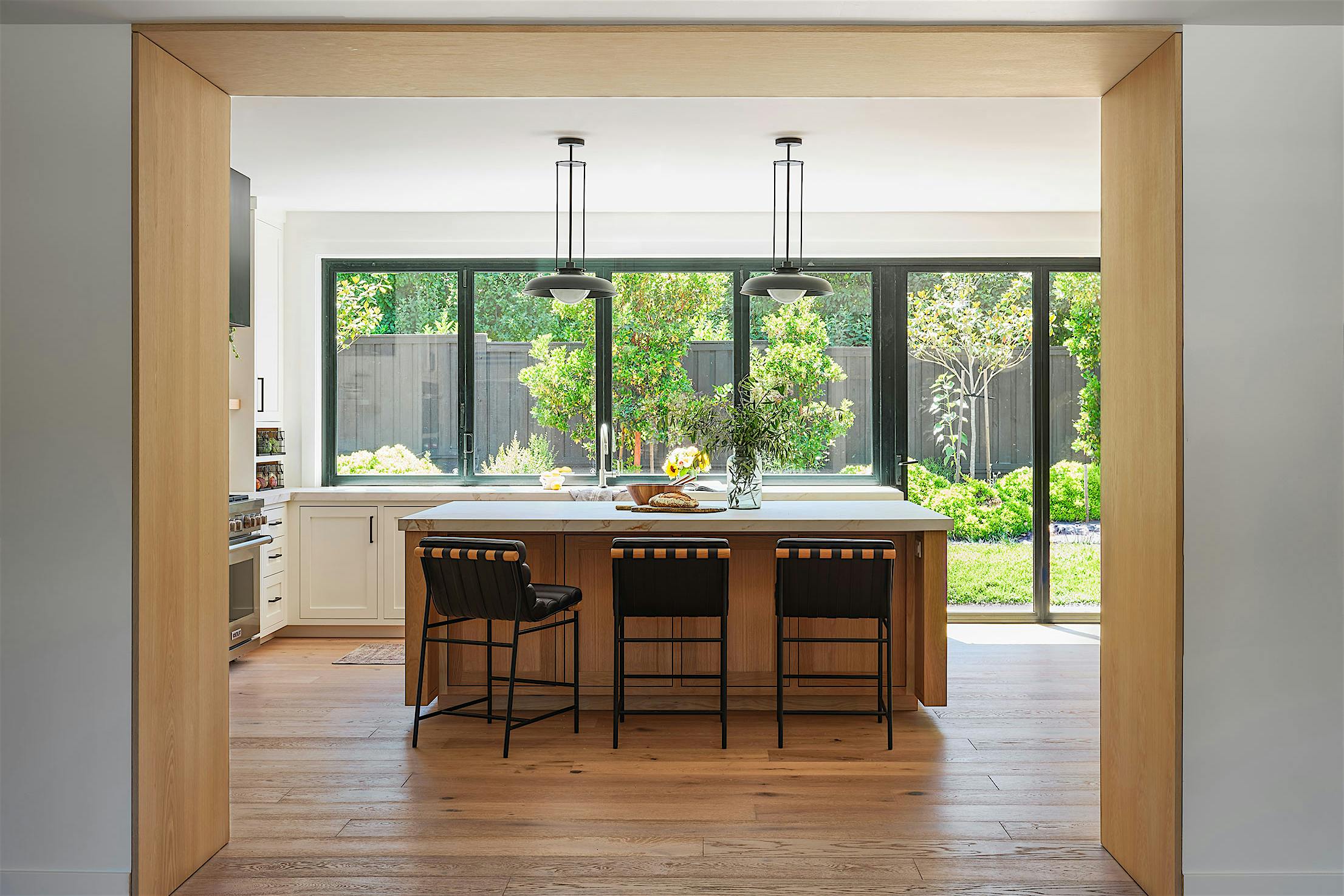 A modern kitchen with a view of the outdoors through an opening glass windows doors conbination
