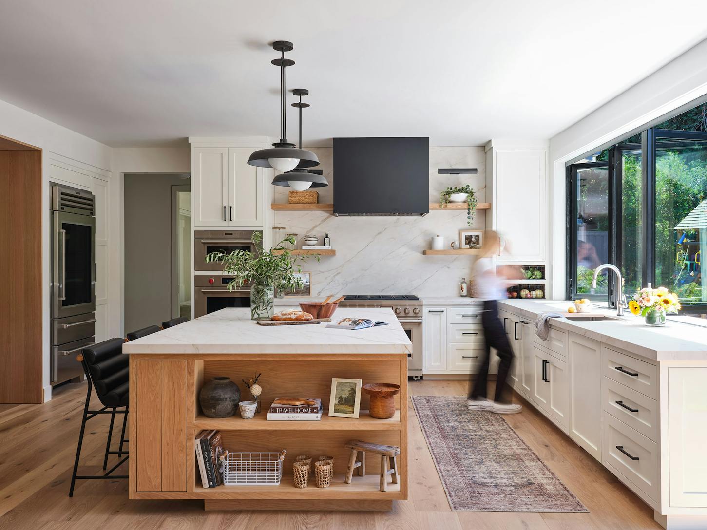 A modern kitchen with a center island, and a window/door combination designed for indoor outdoor open space