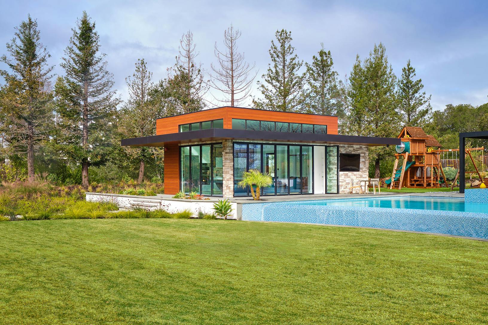 Contemporary pool house with bifold glass walls creating an indoor/outdoor area