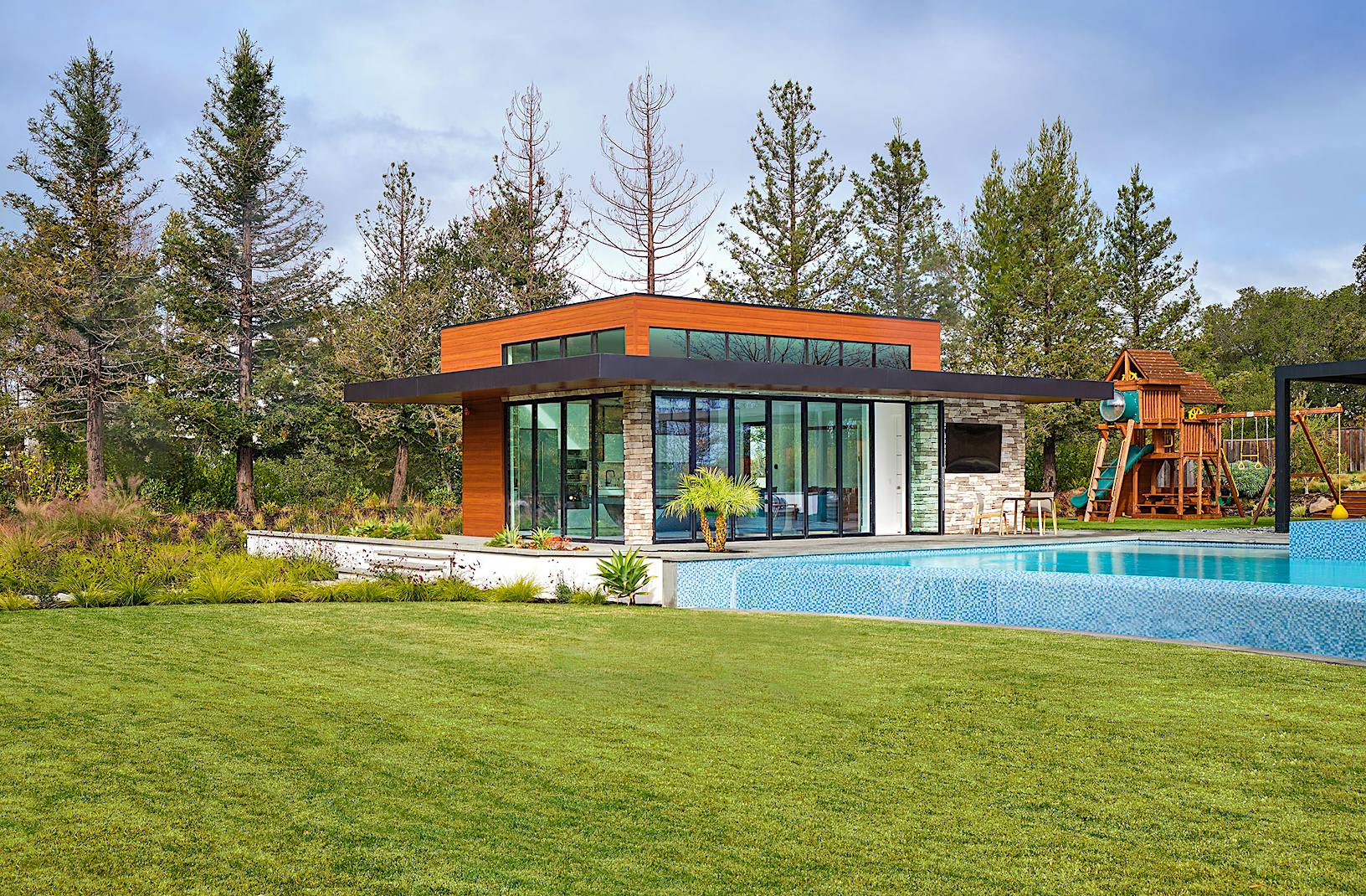 Contemporary pool house with bifold glass walls creating an indoor/outdoor area