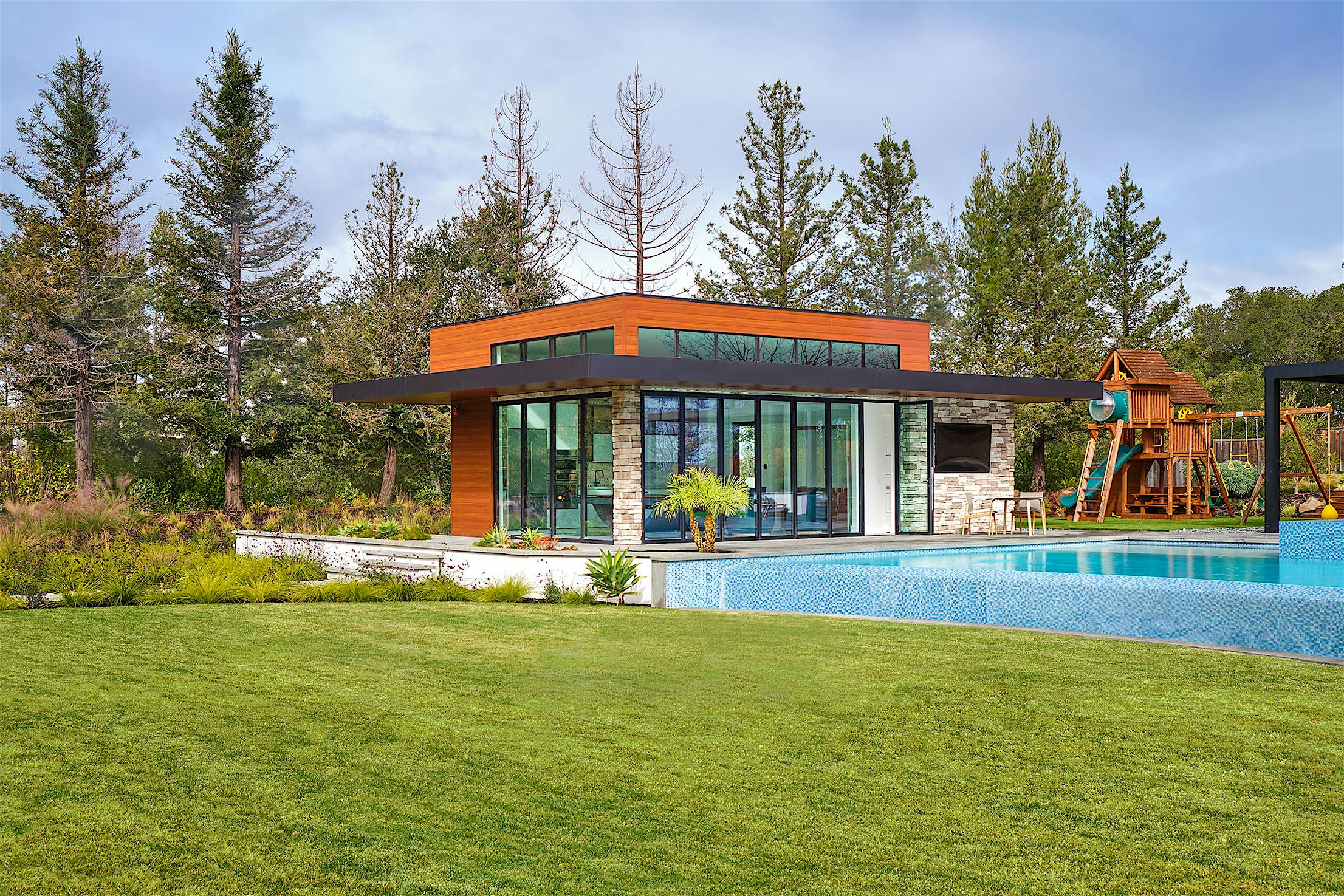 Contemporary pool house with bifold glass walls creating an indoor/outdoor area