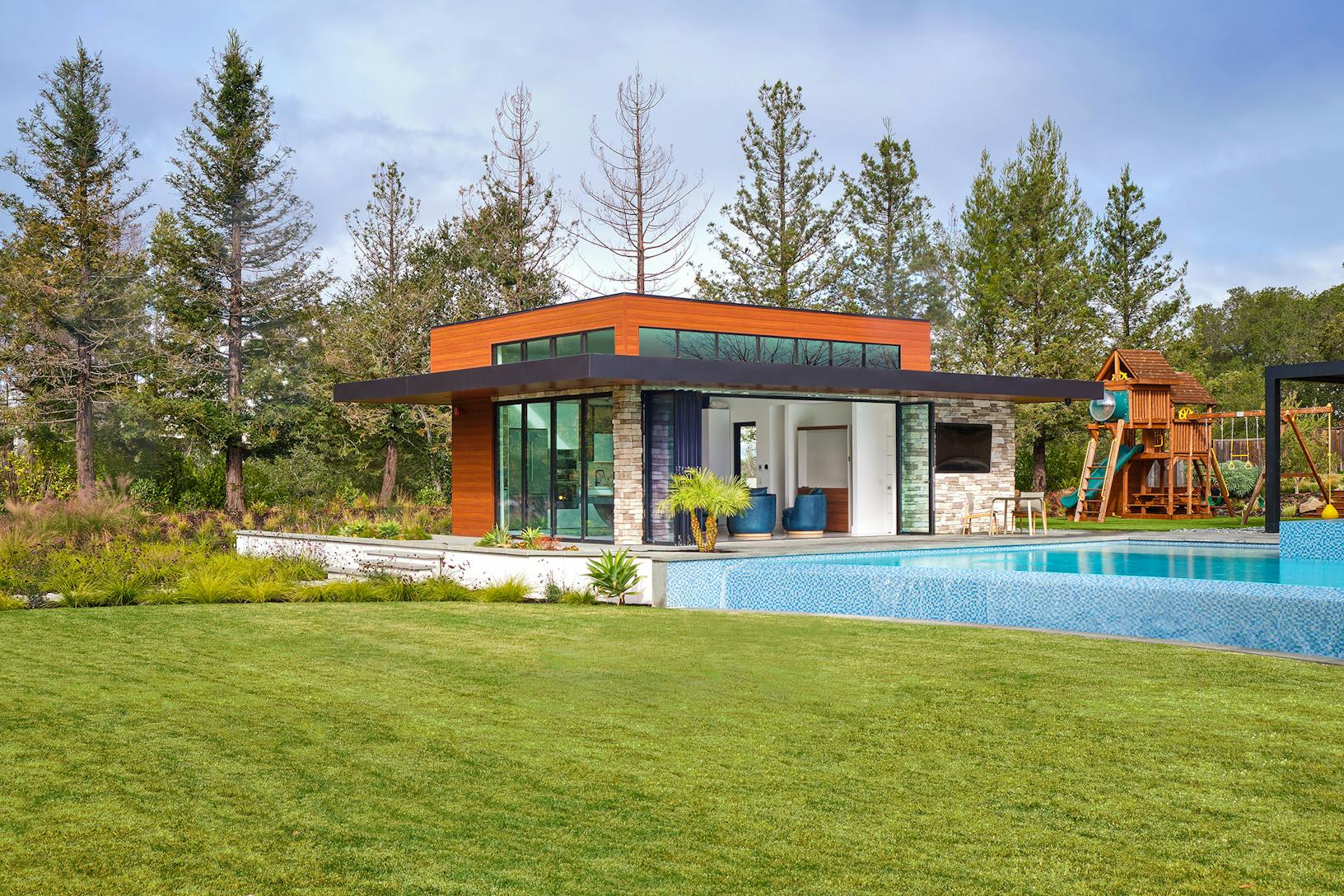 A contemporary home with bifold glass walls and a large swimming pool