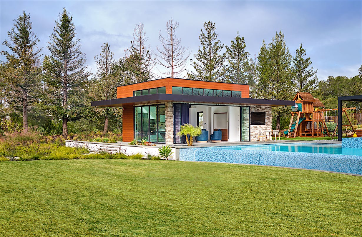 A contemporary home with bifold glass walls and a large swimming pool