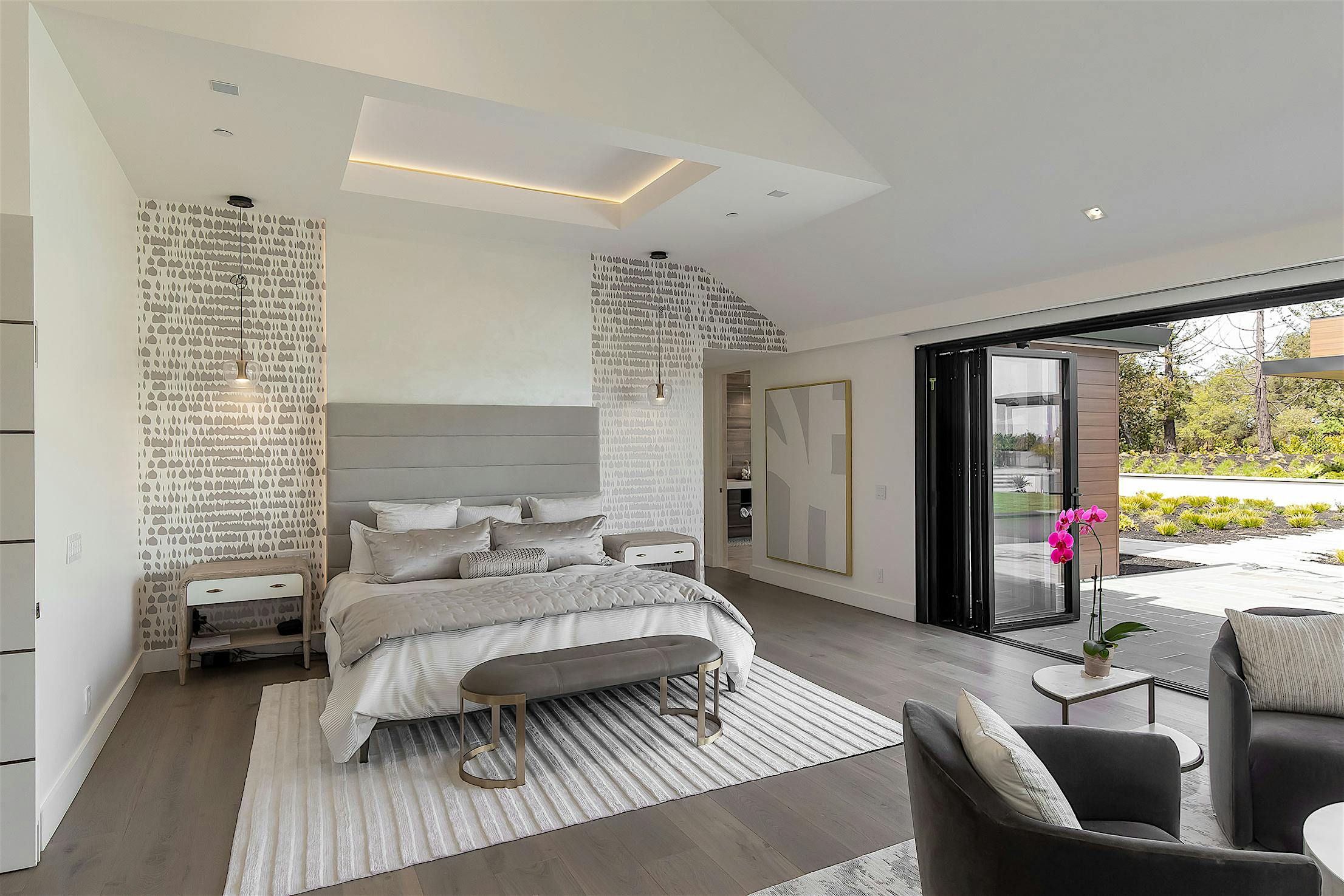 A bedroom with a large bed and folding glass doors