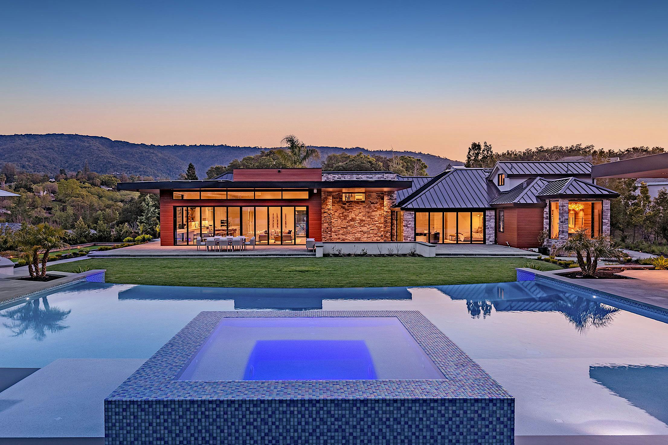 A modern home with bifold glass walls and a large swimming pool
