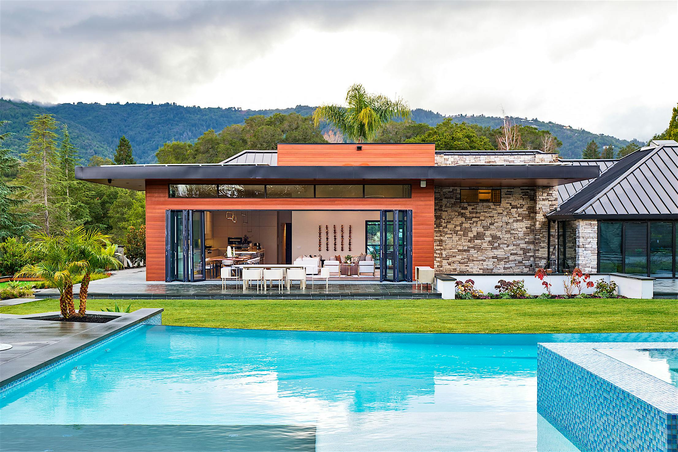A modern house with folding patio doors and a swimming pool.