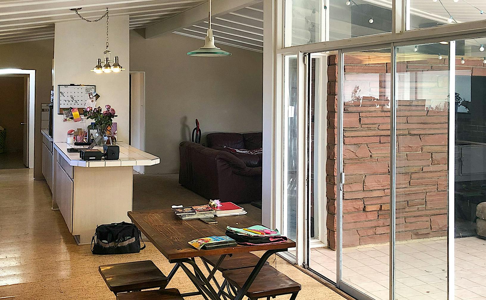 A bright, open-plan living space with large folding glass doors leading to an outdoor area with a brick wall.