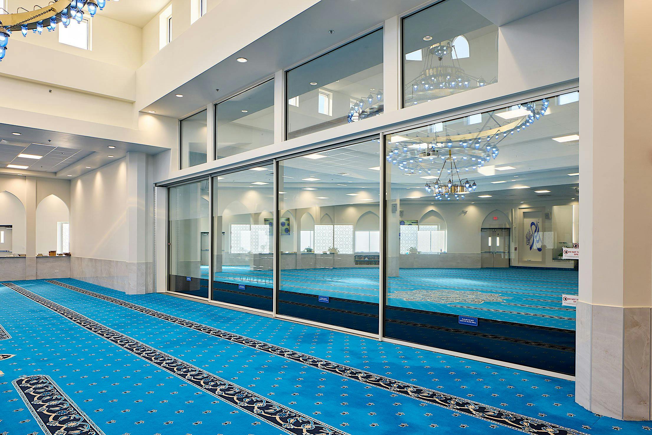 The spacious interior of the mosque features large transoms, complemented by large sliding glass doors.