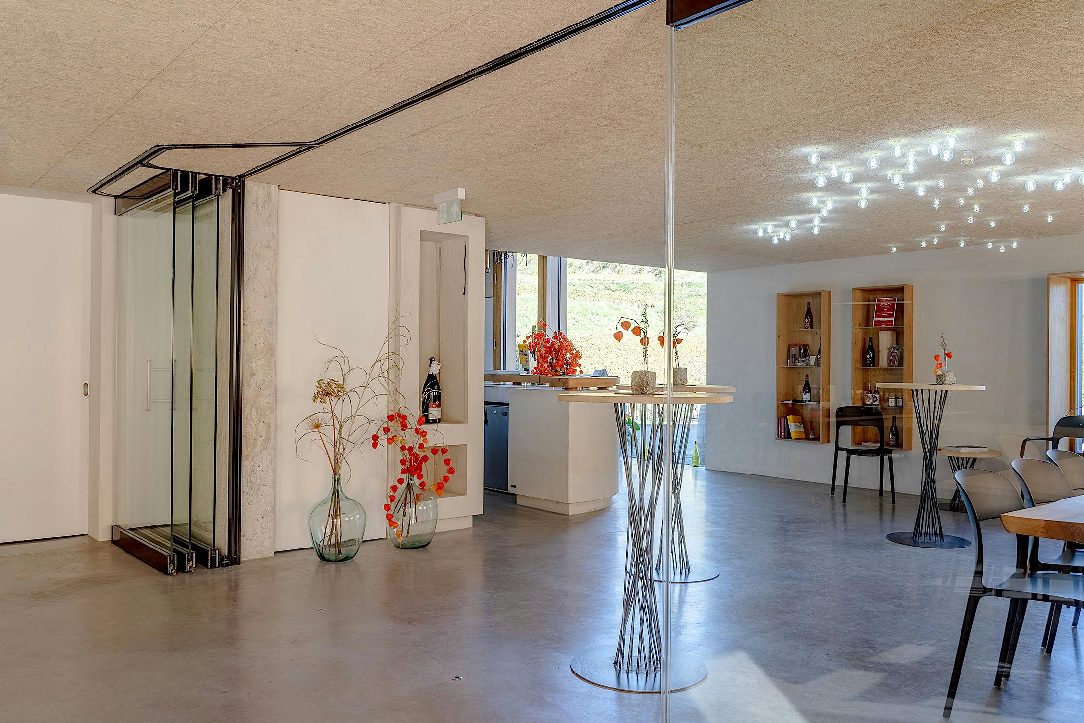 Modern wine tasting room interior with glass partition walls stacked to the left side.