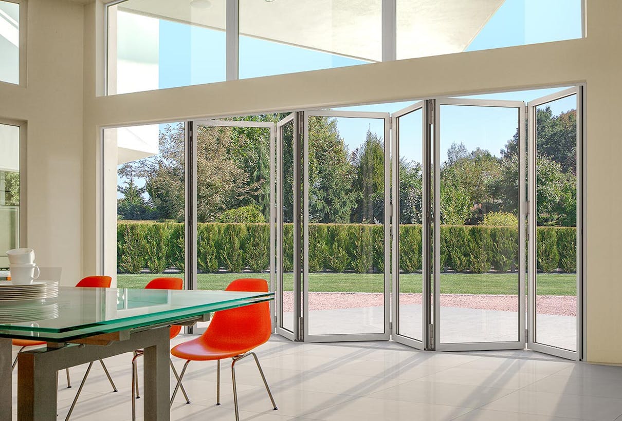A dining room with a glass sliding door, also known as a folding patio door