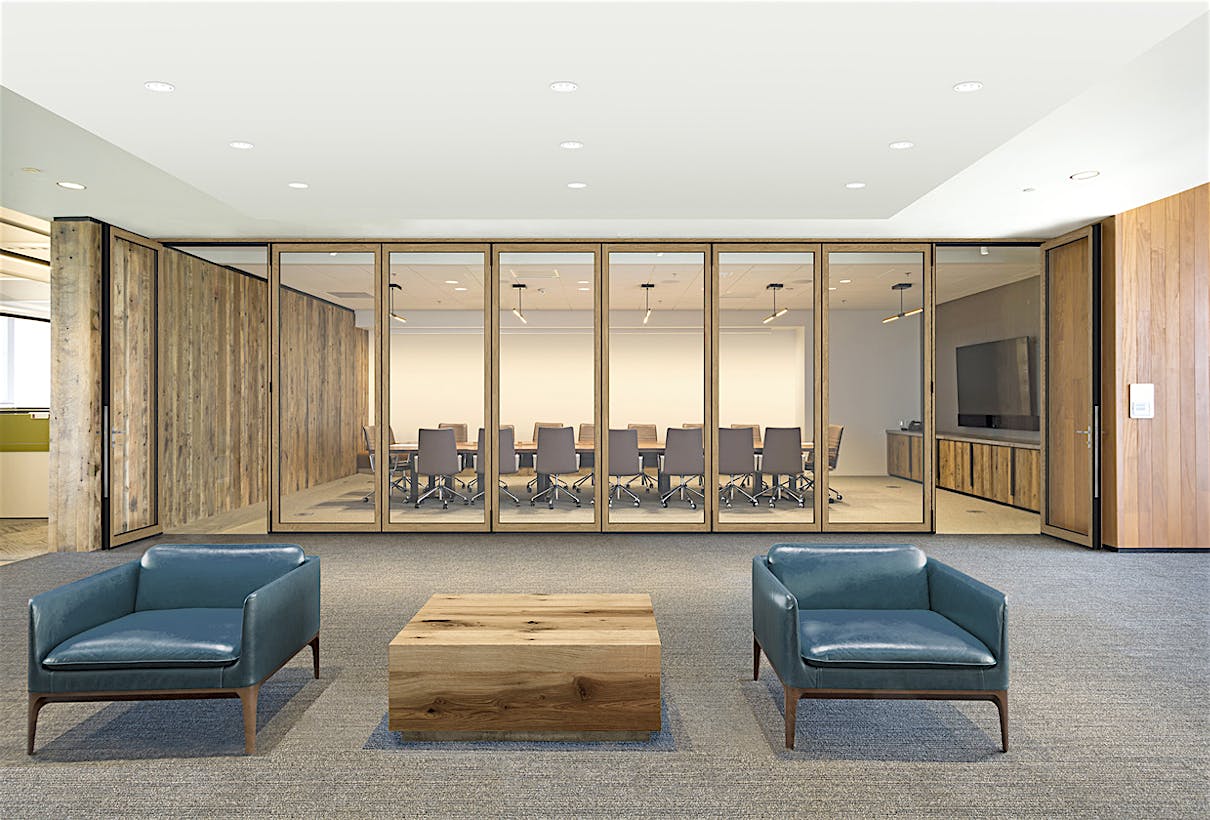 A conference room with acoustical glass walls with two blue chairs and a table