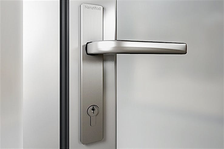 Close-up of a modern stainless steel lever handle and keyhole on a frosted glass door.