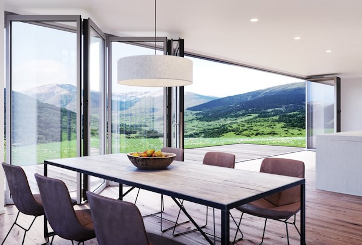 A modern dining room featuring glass walls with a view of the mountains