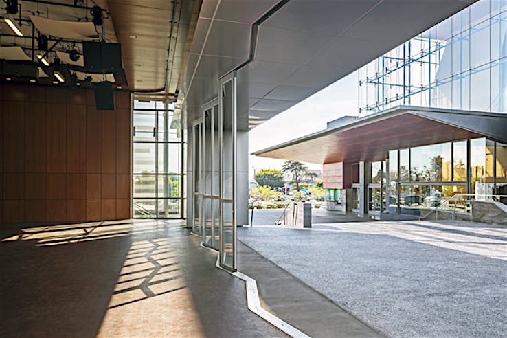 Modern building interior with large sliding glass doors featuring a zig-zag sill design, seamlessly opening to an outdoor area.