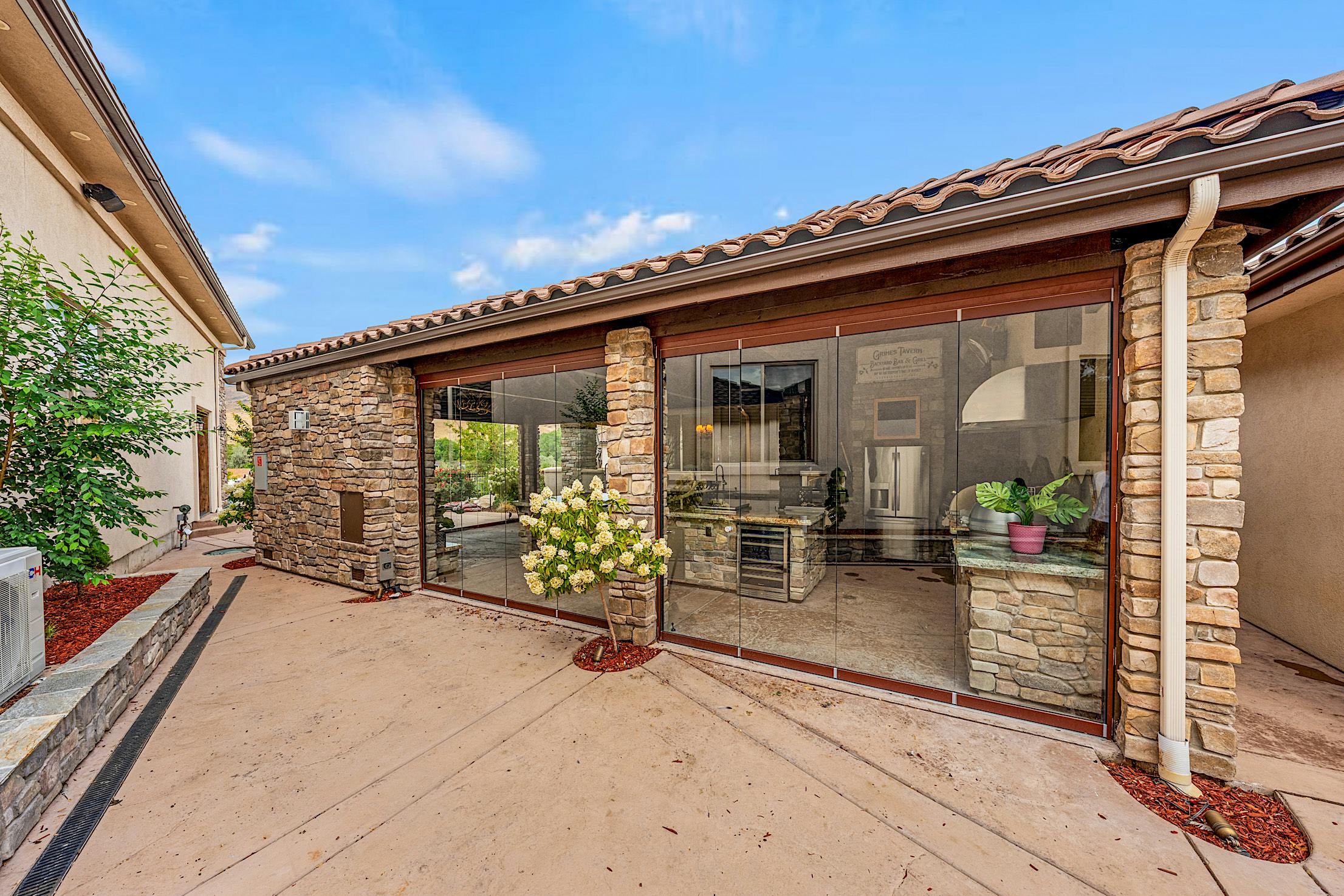all-glass movable glass doors protect outdoor kitchen