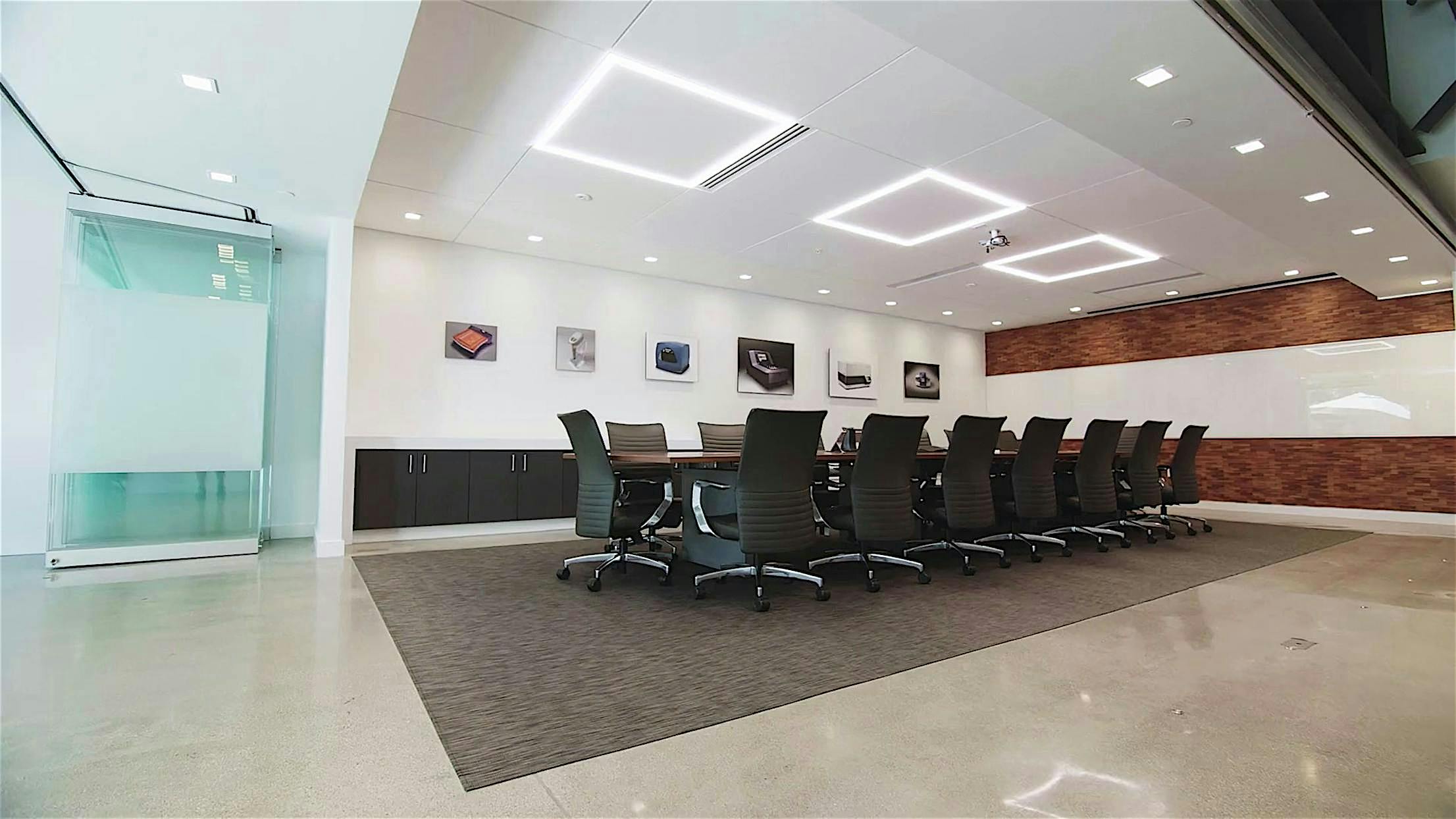 Modern office space with a glass-enclosed conference room with sliding doors and open corner layout.